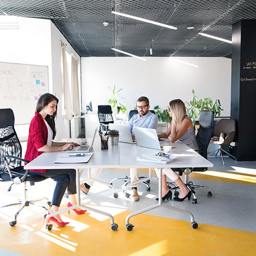 Three professionals working at a modern corporate shared services office space in Costa Rica